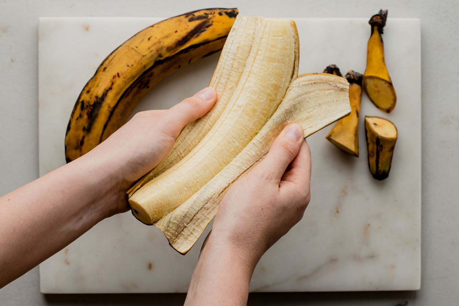 peeling off the backs of the ripe plantain for your Akamu and Dodo breakfast meal